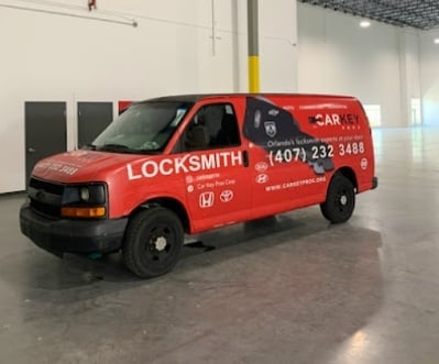 Red locksmith service van parked in a garage with phone number and branding displayed on the side